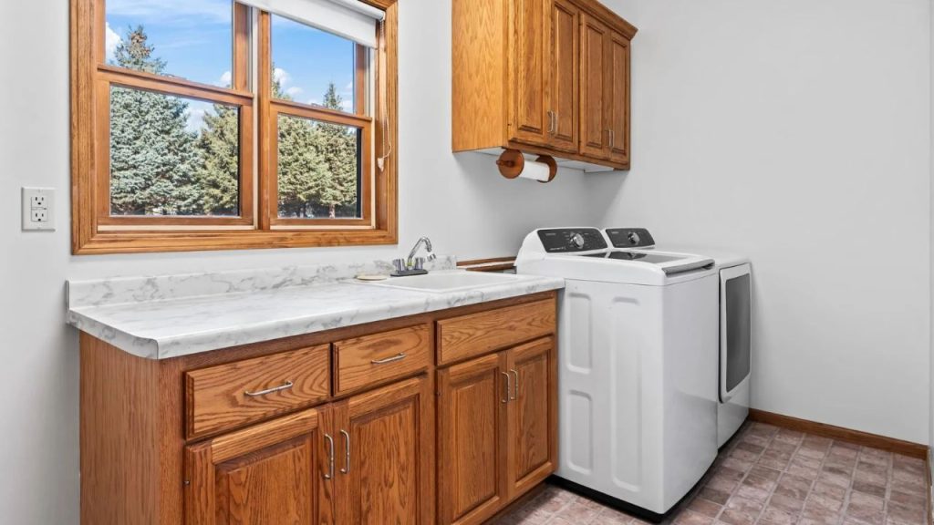 Laundry room with oak cabinets, washer and dryer, and large window.