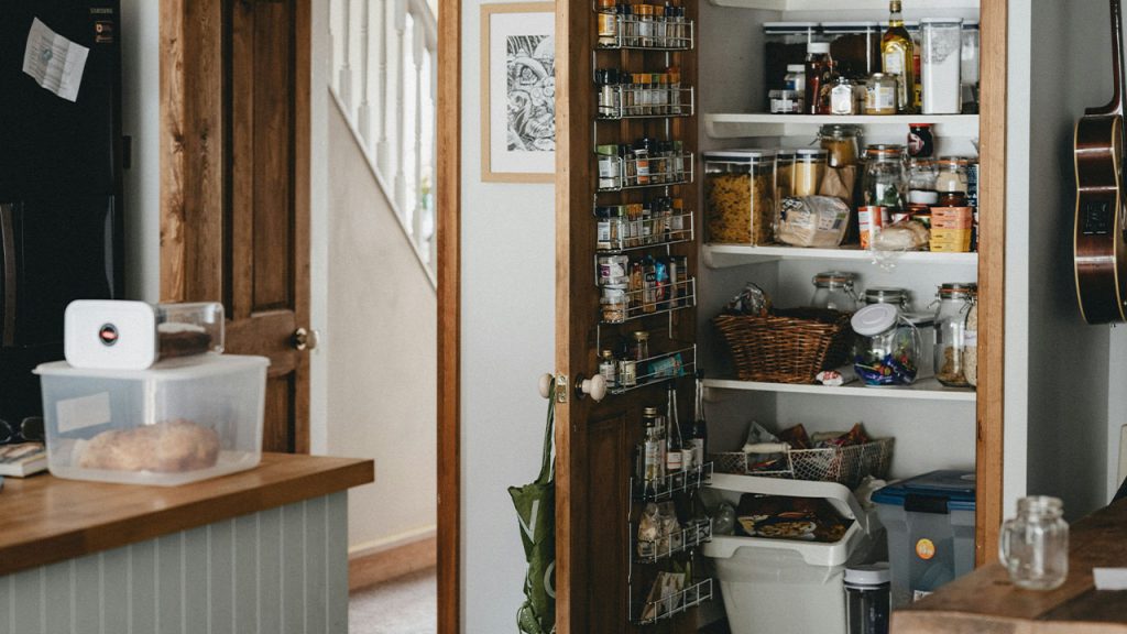 white plastic trash bin beside brown wooden shelf