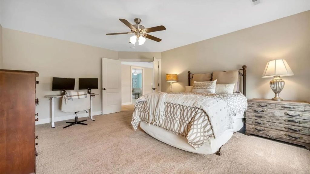 Warm bedroom with a cozy bed, rustic furniture, and a home office setup.