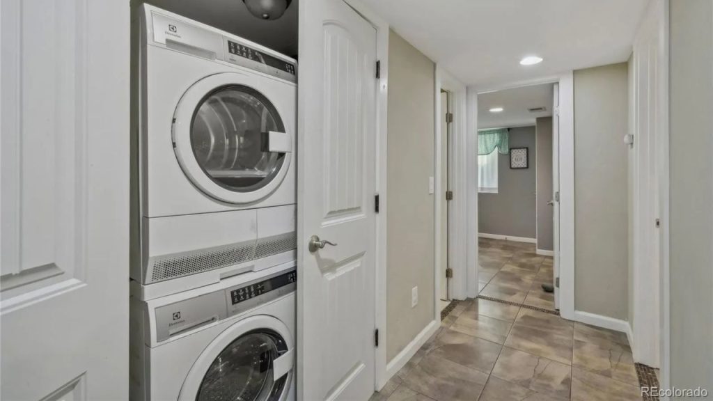 Stacked washer and dryer in a hallway closet with tiled flooring.