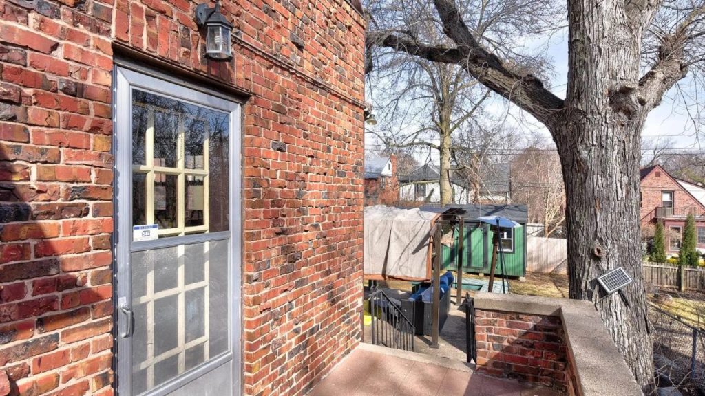 Brick home with side entry door and view of backyard patio.