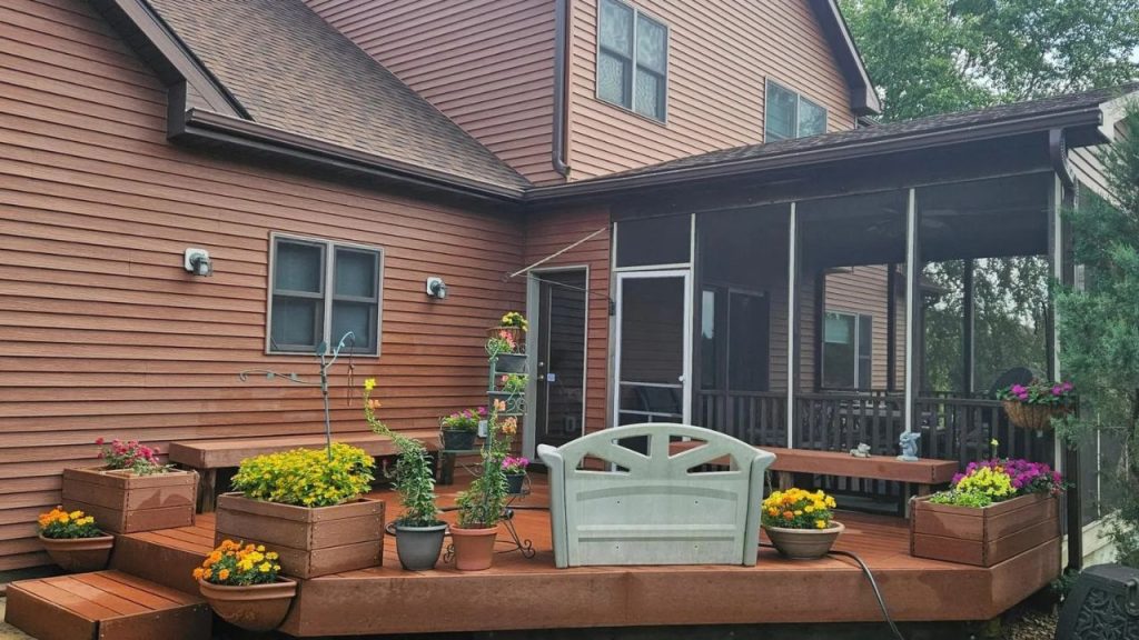 Wood deck with potted flowers and a screened porch.