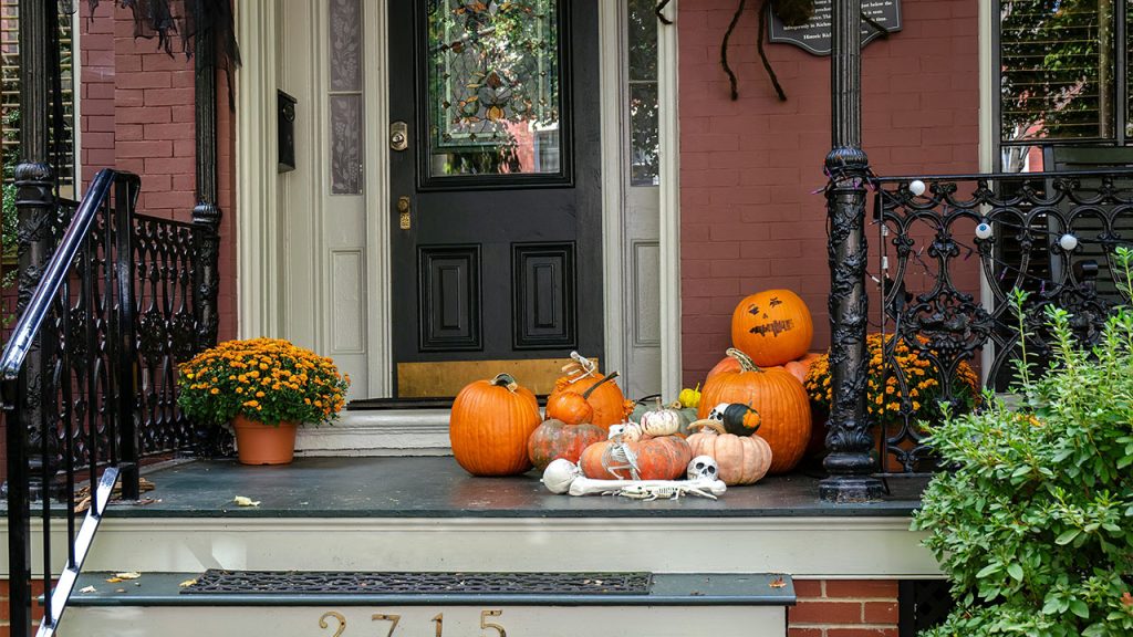 a front porch decorated for halloween with pumpkins and gourds