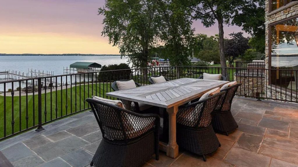Lakeside dining terrace with a wooden table and cushioned chairs.