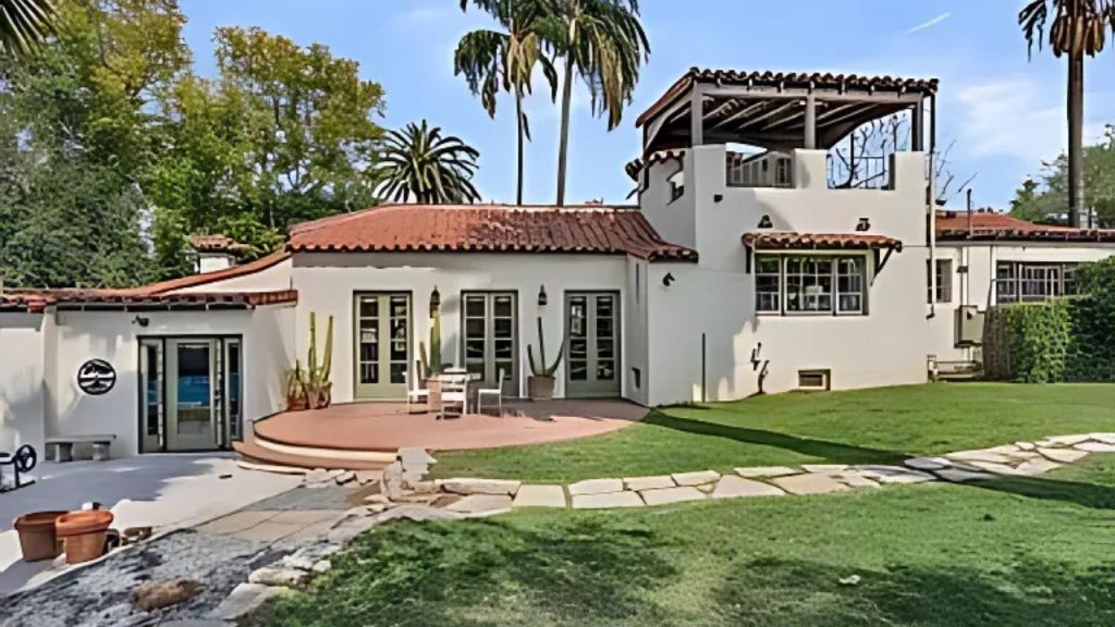 Spanish-style home with red tile roof and grassy backyard.