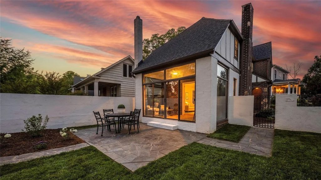 A cozy patio with a table and chairs, glowing glass extension, and a colorful sunset sky.