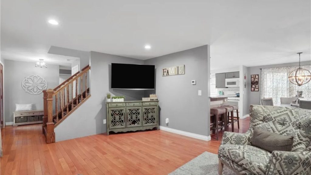 Cozy open living area with hardwood floors, gray walls, and staircase.