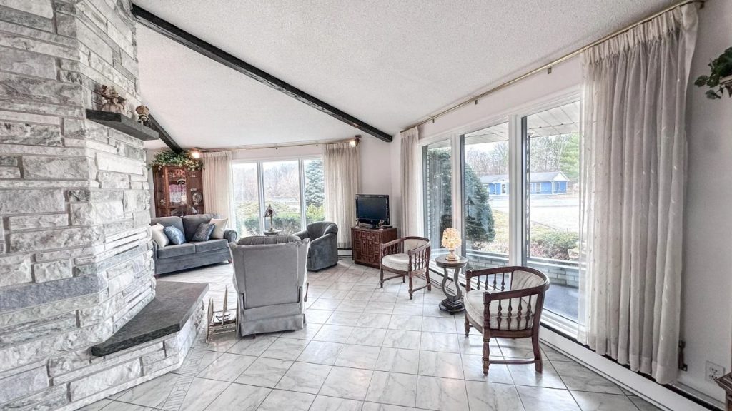 Bright living room with stone fireplace and large windows.