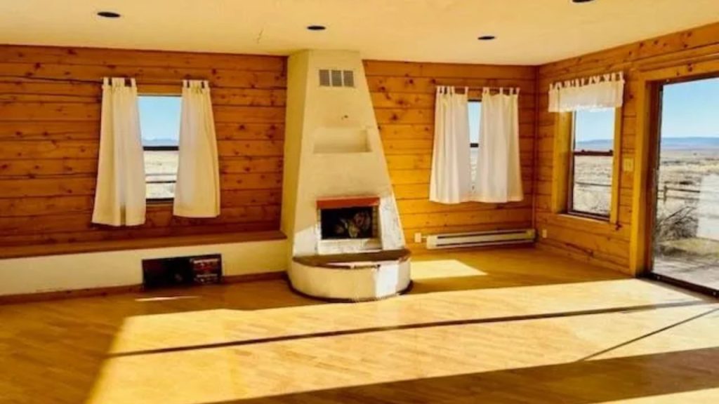 Bright living room with wood walls and adobe fireplace.