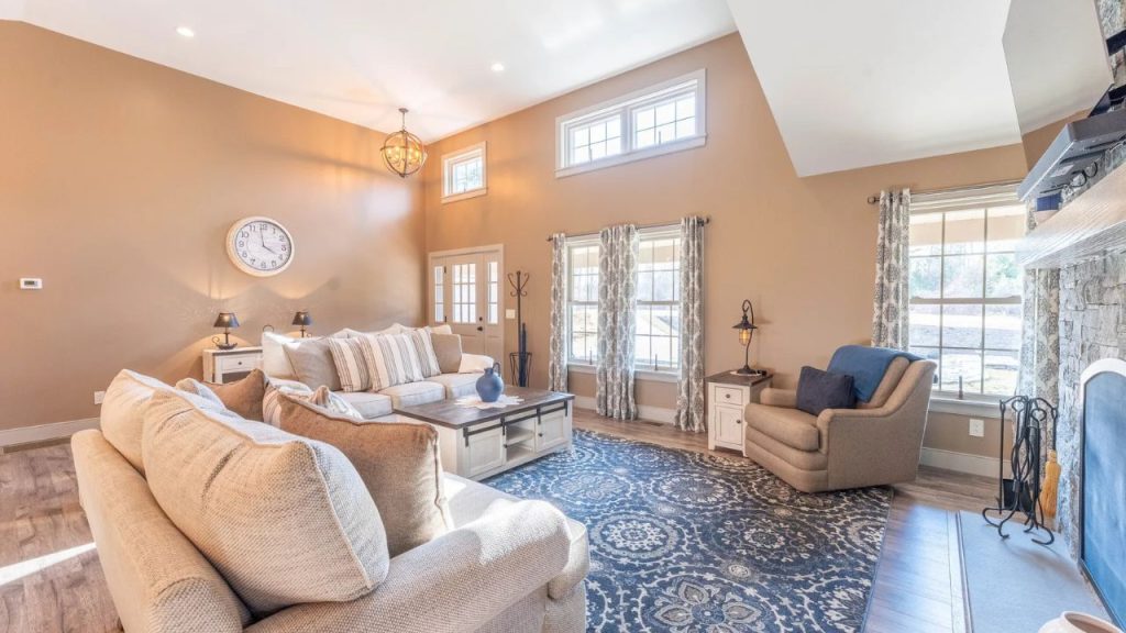 Bright and cozy living room with high ceilings, plush seating, and a stone fireplace.