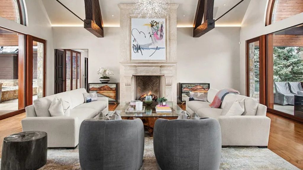 Cozy living room with a stone fireplace, modern furniture, and large windows.