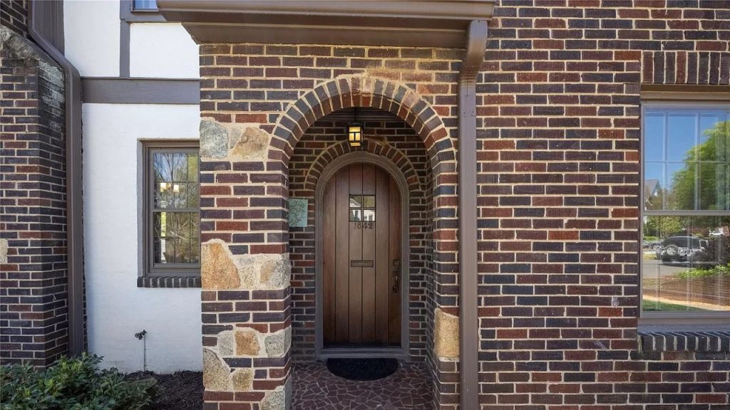 A cozy front entry with a wooden door, brick archway, and warm lantern light.
