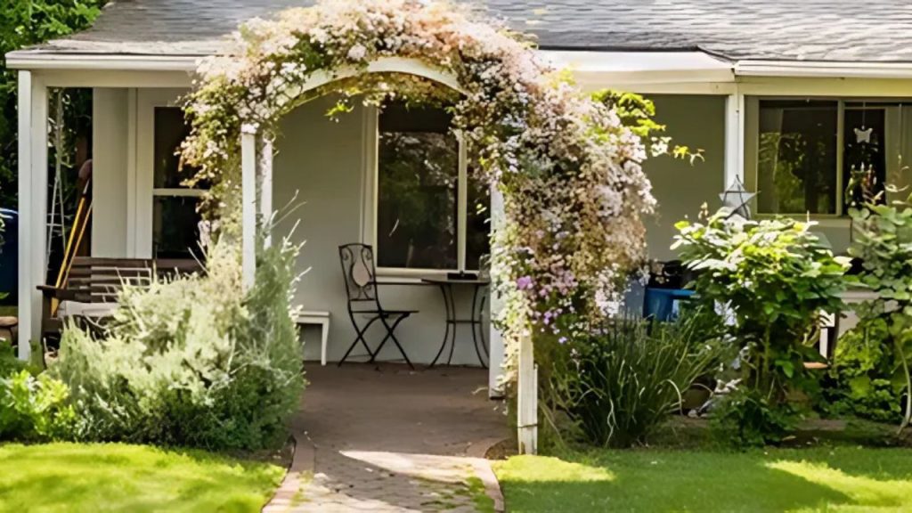 A cozy front porch with a flower-covered archway, small table, and lush greenery.