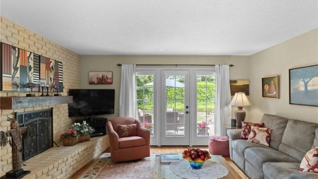 Bright family room with brick fireplace, cozy seating, and French doors to patio.