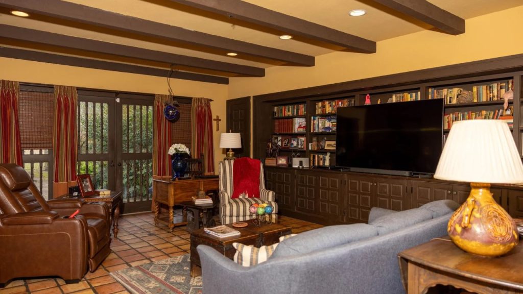 Warm and cozy living room with exposed beams, built-in bookshelves, and a mix of classic and comfortable furniture.