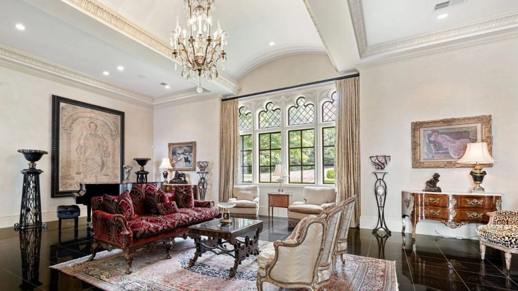 Elegant living room with Gothic windows, chandelier, and antique-style furnishings.