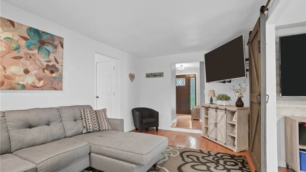 Cozy den with a gray sectional, barn door, and soft rustic decor.