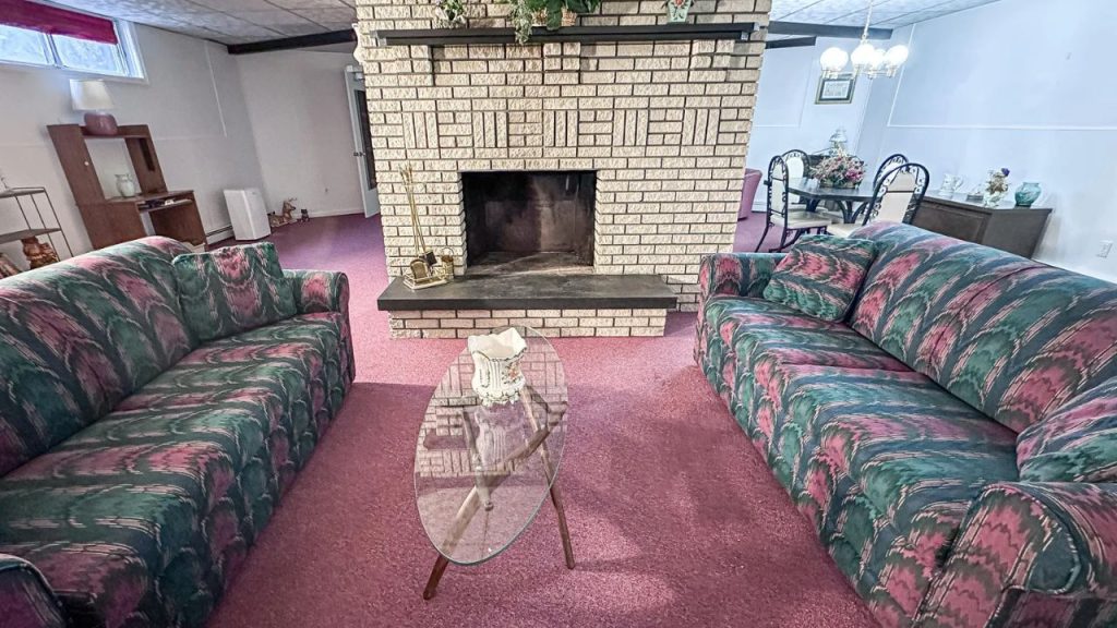 Cozy basement lounge with patterned carpet and brick fireplace.