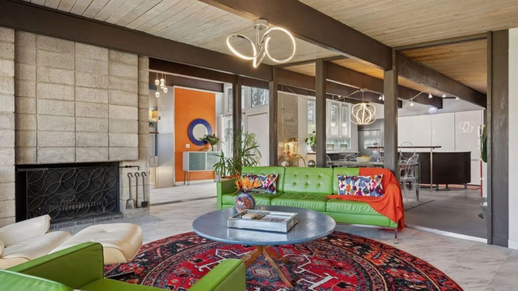 Colorful living room with green sofas, red rug, and stone fireplace.