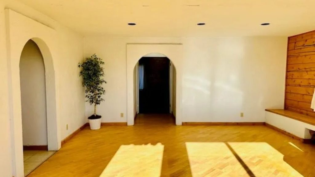 Sunlit hallway with arches and wood floors.