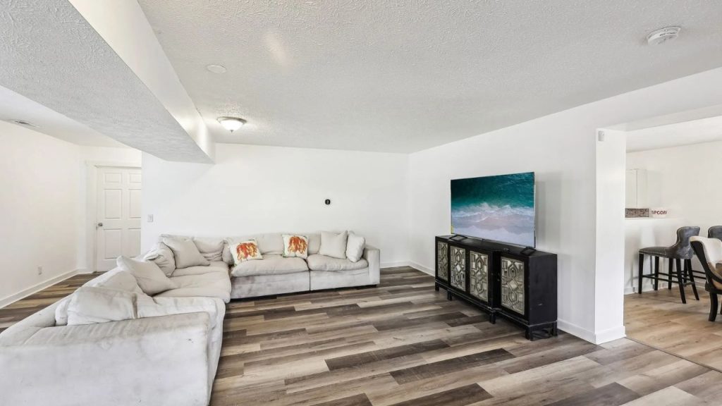 Living room with sectional sofa, flat-screen TV, and open layout to kitchen.