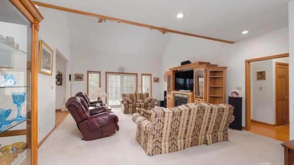 Bright living room with vaulted ceilings, plush seating, and a wooden entertainment center.