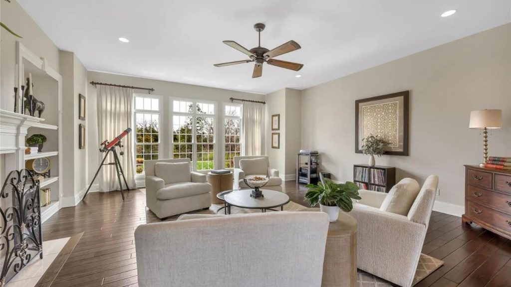 Cozy living room with large windows, neutral furniture, and a fireplace.