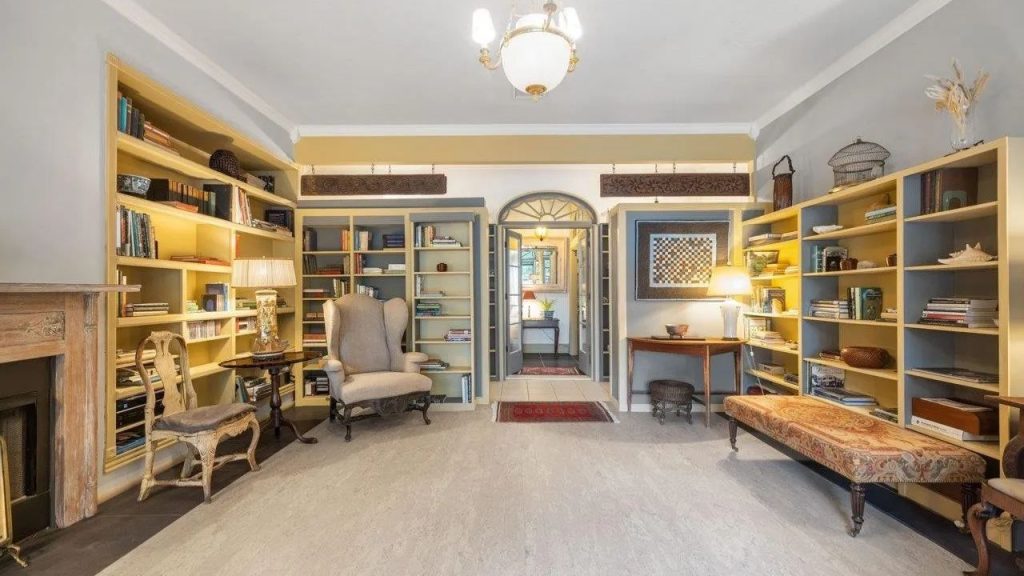 Cozy library with built-in bookshelves, antique furniture, and warm lighting.