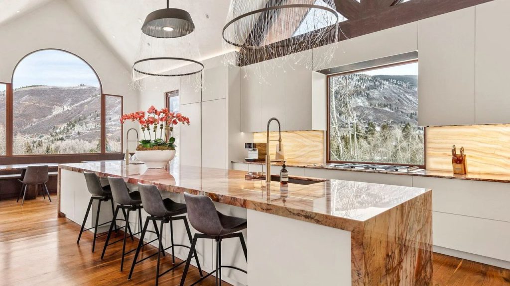 Stylish kitchen with a marble island and mountain views through large windows.