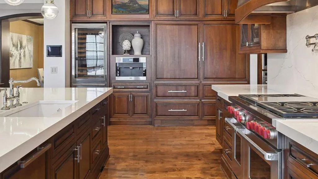 A stylish kitchen with dark wood cabinets, white marble counters, and a modern stainless steel range.