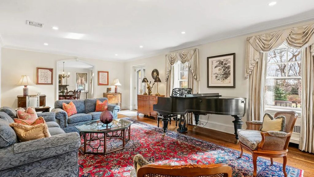 A stylish room featuring a grand piano, plush sofas, and large windows with elegant curtains.