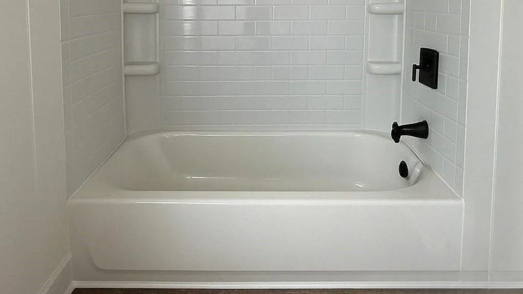 White bathtub with subway tile walls and black fixtures.