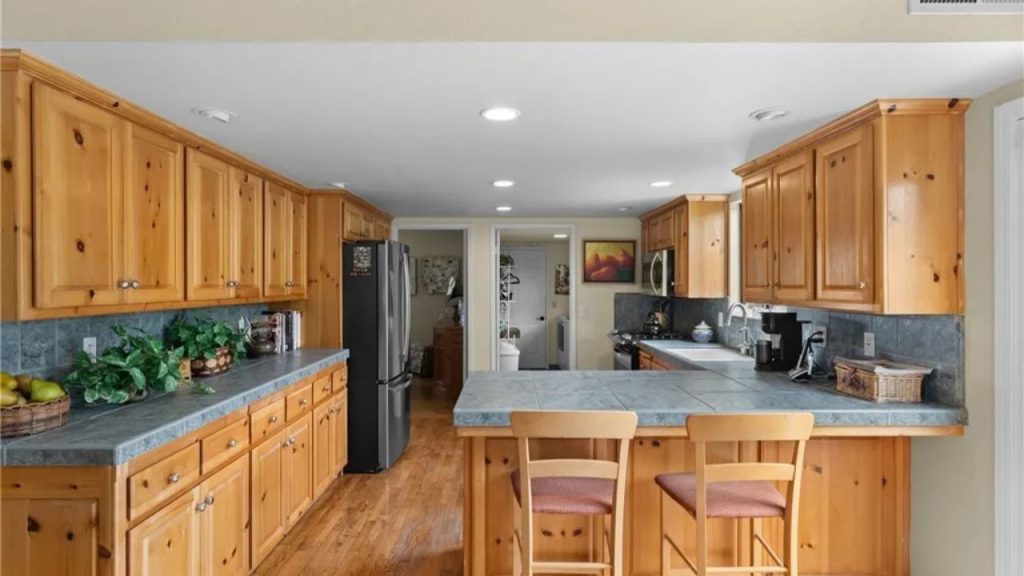 Rustic kitchen with wood cabinets, blue counters, and bar seating.