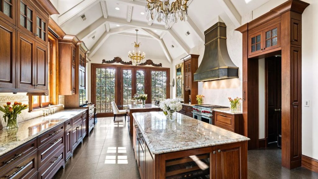 Luxurious kitchen with wood cabinetry, chandeliers, and granite countertops.