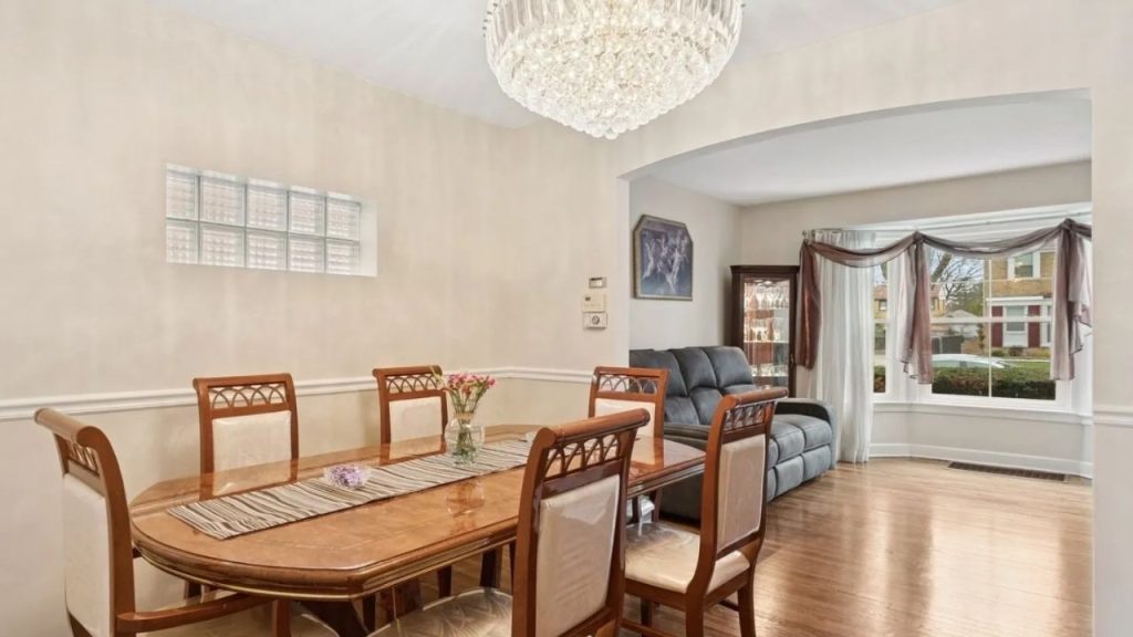 Elegant dining room with chandelier and wood furniture, opening into a cozy sitting area.