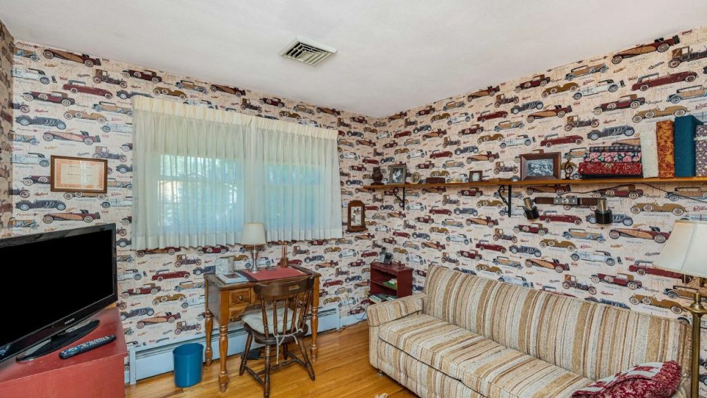 Study room with vintage car wallpaper, striped couch, and antique desk under soft window light.