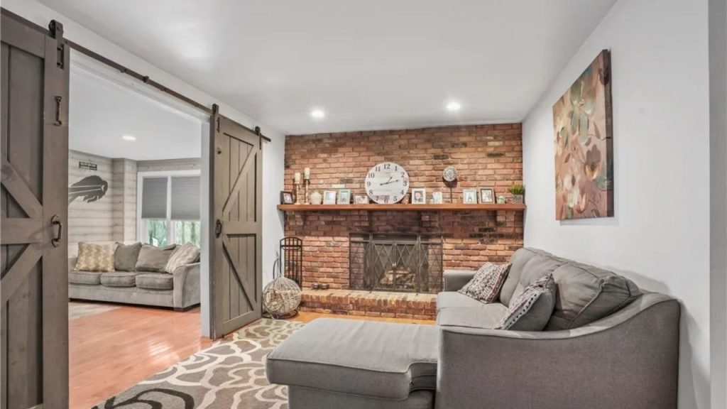 Cozy room with brick fireplace, barn doors, and soft gray furniture.