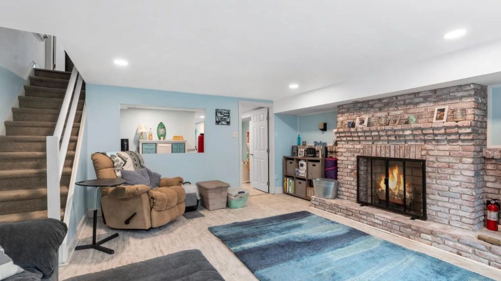 Basement living area with brick fireplace, recliner, and soft lighting.
