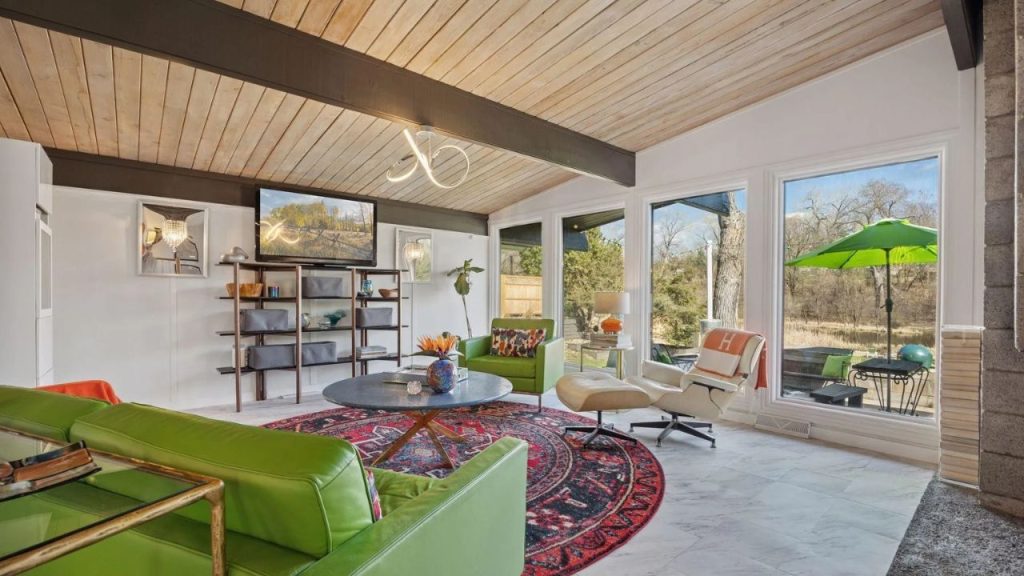 Bright living room with green chairs, large windows, and garden views.