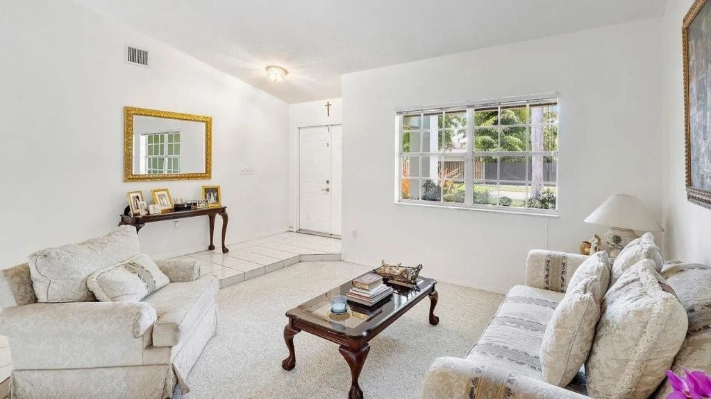 A cozy sitting area with cream sofas, a wooden coffee table, and a bright window view.