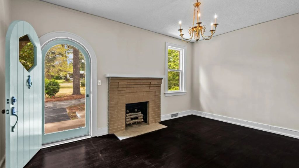 Living room with fireplace, chandelier, and arched door.