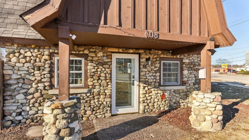 Cozy stone cottage entrance with wood trim and a glass front door.