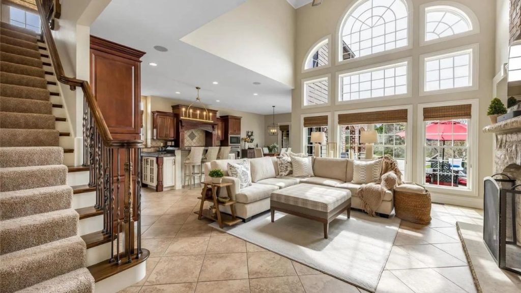 Spacious living room with large arched windows, cozy seating, and an open kitchen.