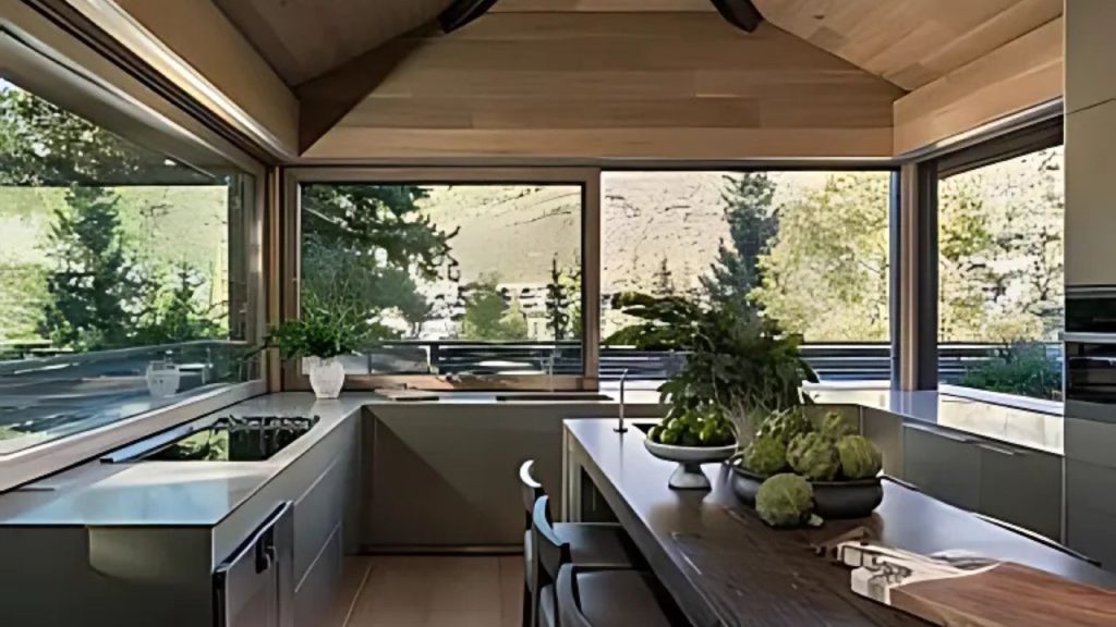 A modern kitchen with wooden ceilings, large windows, and a view of greenery.