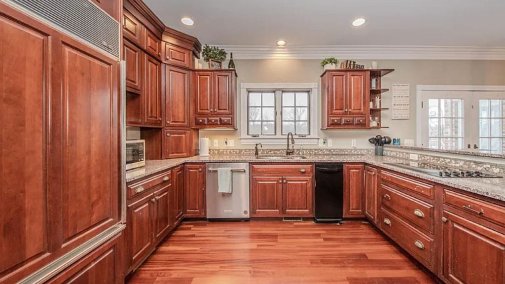 A spacious kitchen with cherry wood cabinets, granite countertops, and large windows.
