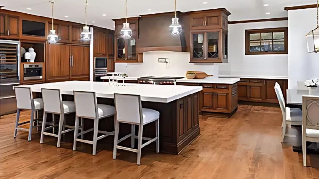 A warm kitchen with dark wood cabinets, a large white island, and hanging pendant lights.