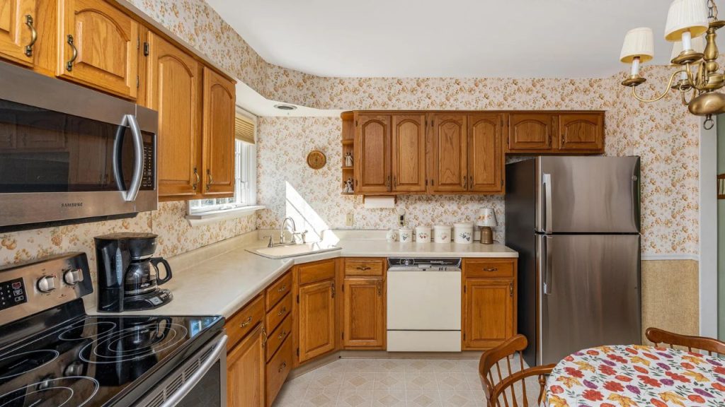 Warm kitchen with wooden cabinets, floral wallpaper, and cozy breakfast nook.