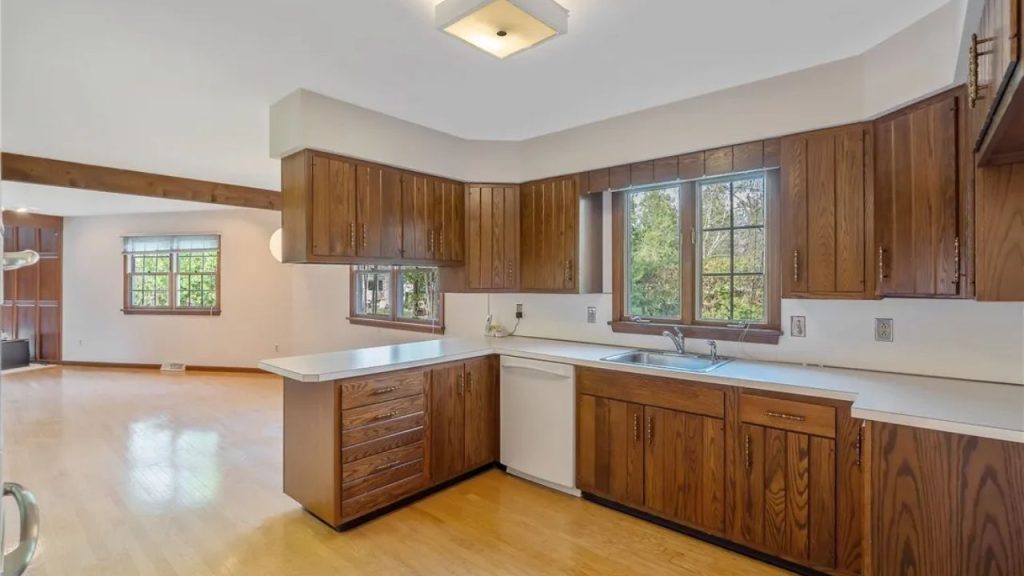 Wood-toned kitchen with white counters and window view of greenery.