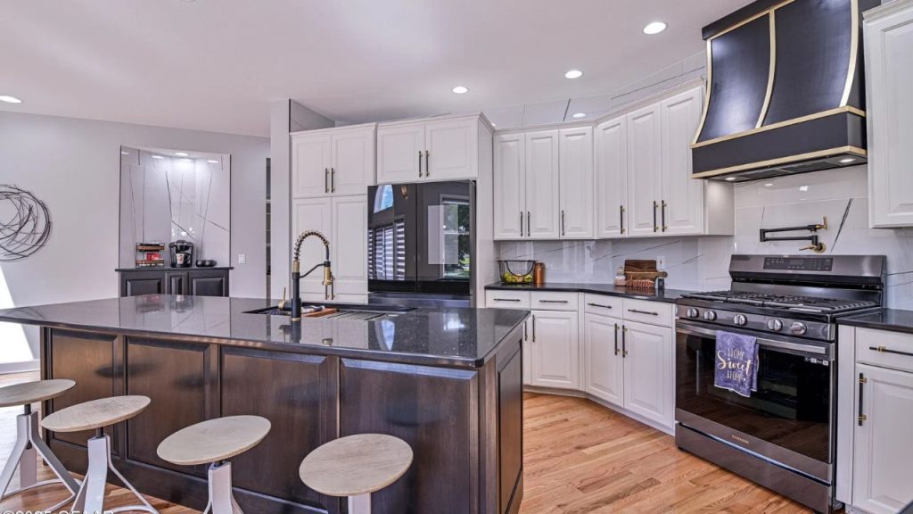 Chic black and white kitchen with brass accents and wood flooring.