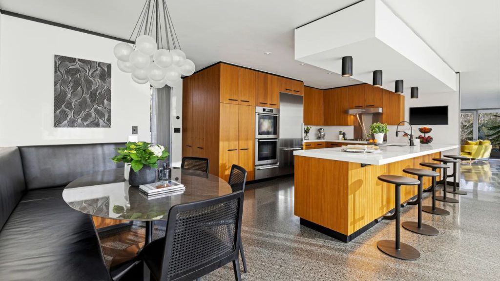Mid-century modern kitchen with wood cabinets, white island, and cozy breakfast nook.